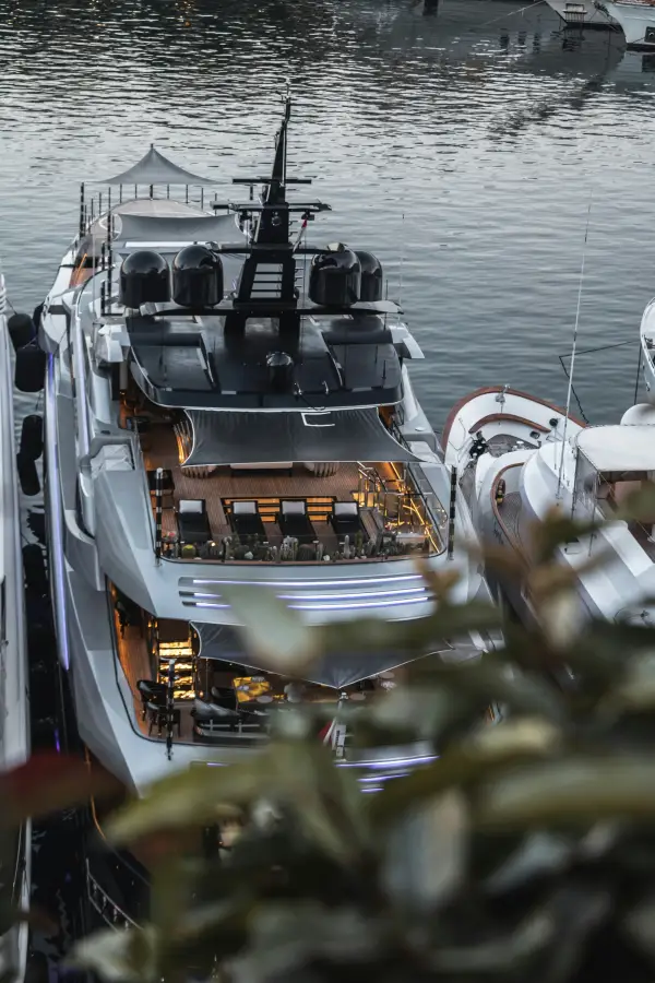Aerial view of a luxury superyacht docked in a marina at dusk; with illuminated decks and cruise amenities visible.