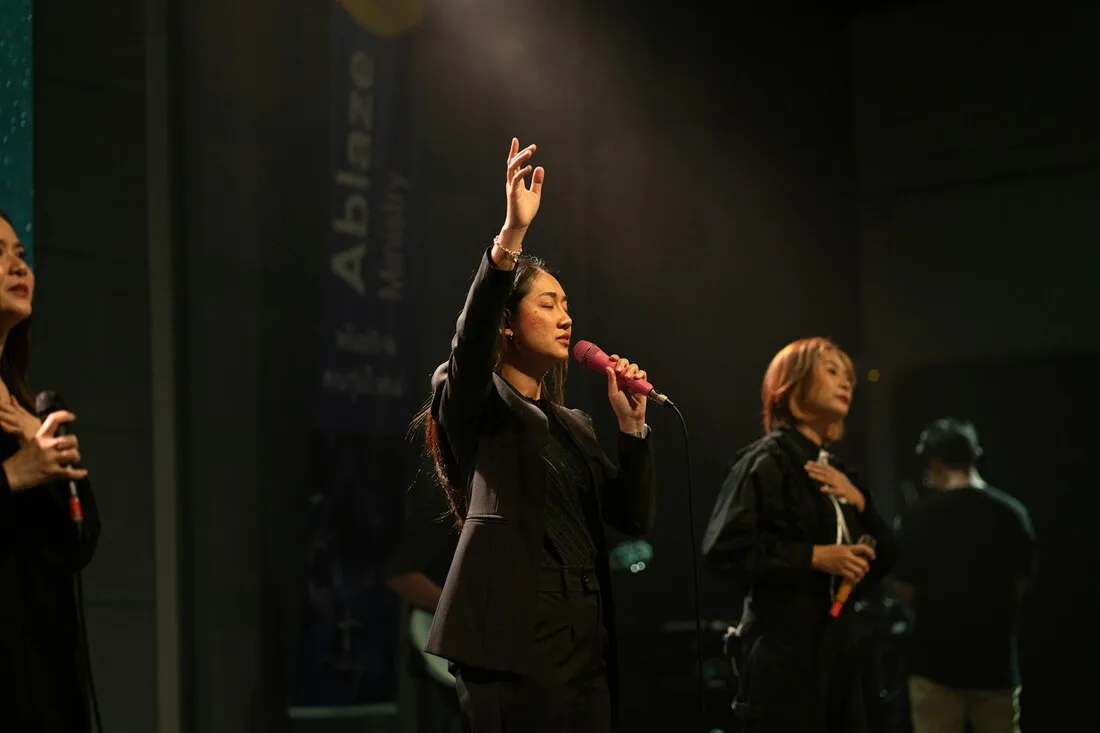 A vocalist performing gospel and soul music with a hand raised under stage lights at a Juneteenth celebration