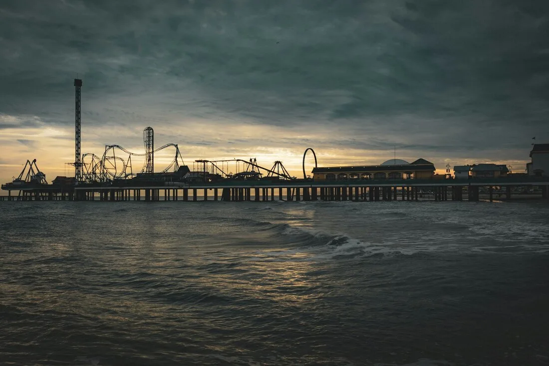 The Galveston Island Historic Pleasure Pier roller coaster silhouetted over the Gulf of Mexico at dusk