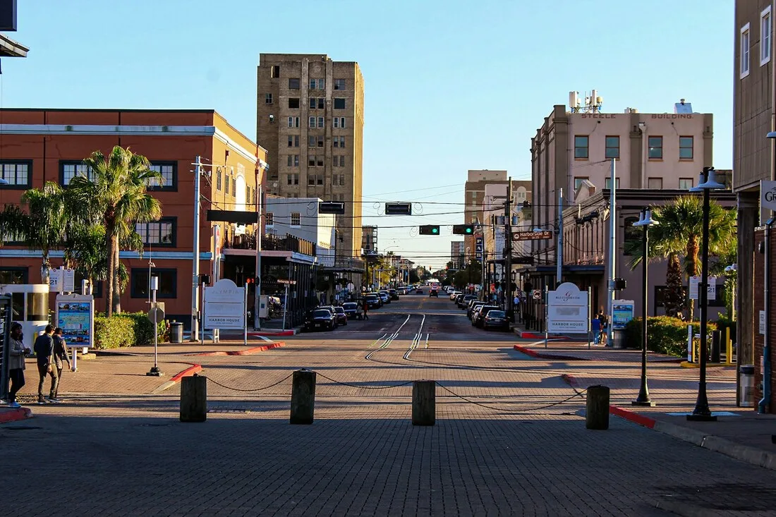 The historic Strand district in Galveston, Texas with brick streets, palm trees, and 19th-century commercial buildings