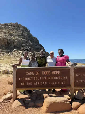 Five travelers smiling at the Cape of Good Hope sign; most south-western point of Africa; during eat-mea-2026 tour.