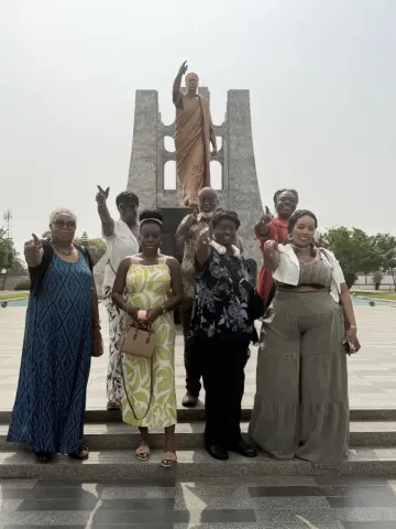 Group of travelers posing at Kwame Nkrumah Memorial Park in Accra; Ghana during eat-mea-2026 tour; pointing toward camera.