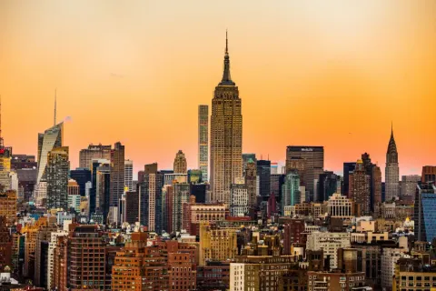 New York New York midtown Manhattan skyline at sunset featuring the Empire State and Chrysler Buildings against an orange and pink sky