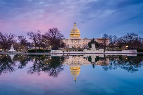 Washington DC US Capitol Building illuminated at twilight reflected in the Capitol Reflecting Pool under a purple and pink sky