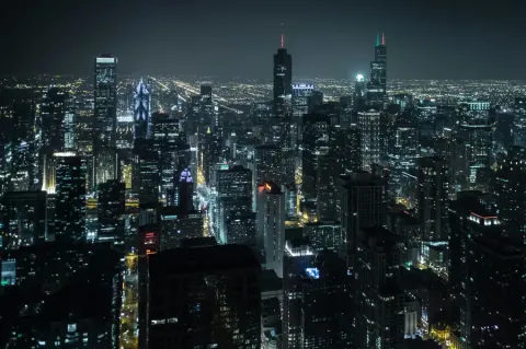 Chicago skyline at night viewed from above; with glittering skyscrapers and city lights stretching to the horizon.