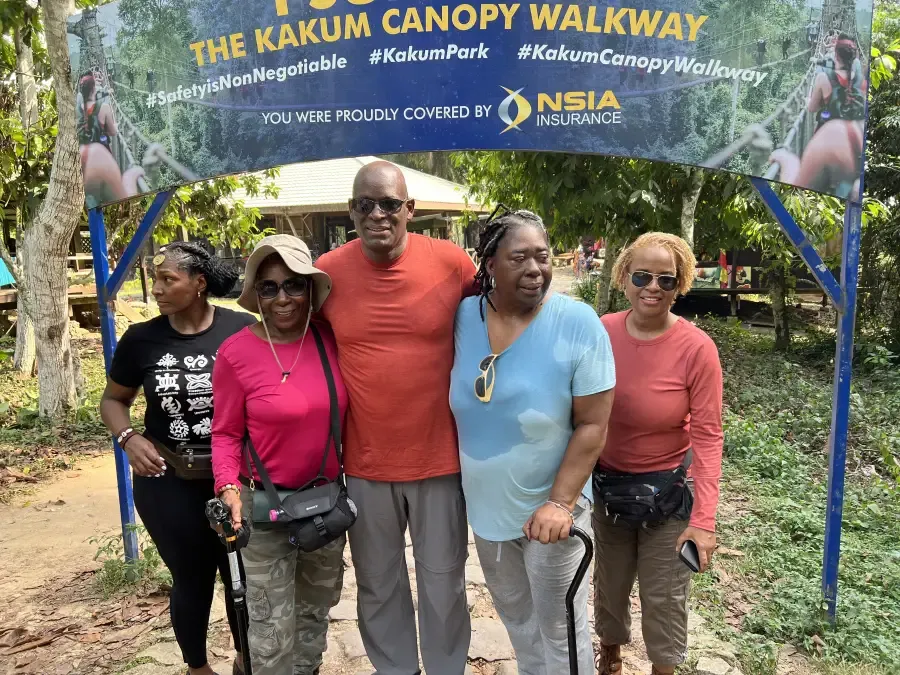 Five travelers pose under the Kakum Canopy Walkway sign in Ghana during the eat-mea-2024 tour; covered by NSIA Insurance.