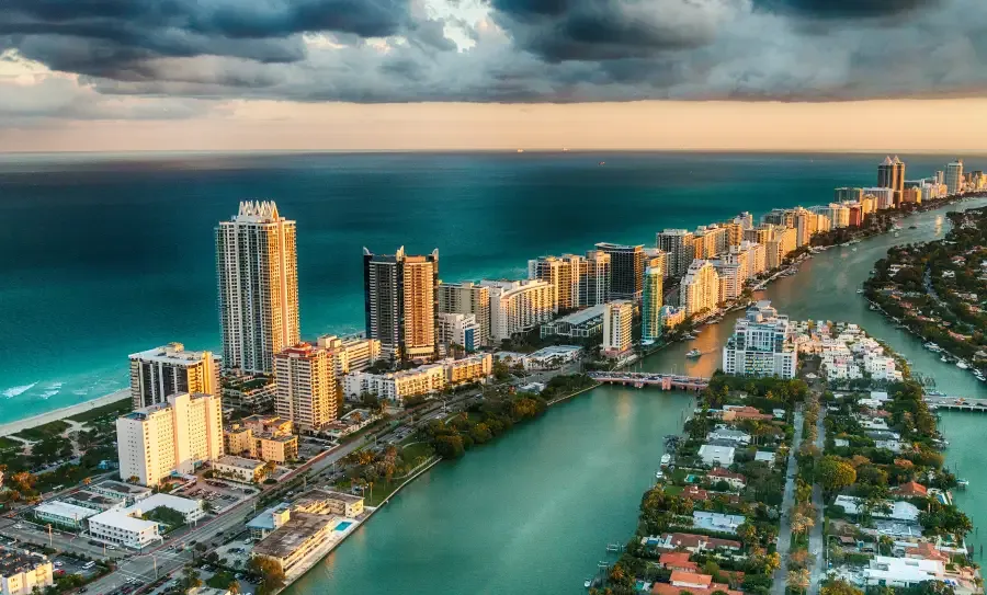 Aerial sunset view of Miami Florida's South Beach skyline with turquoise Atlantic Ocean and Intracoastal Waterway below stretching to the horizon