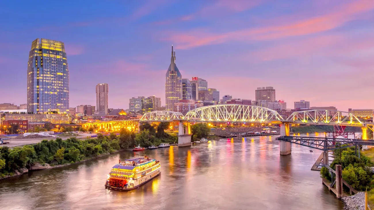 Nashville Tennessee skyline at dusk with a riverboat on the Cumberland River and illuminated Woodland Street Bridge