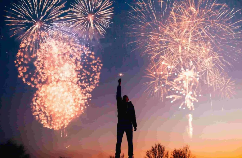 A person silhouetted by fireworks for a destination guide