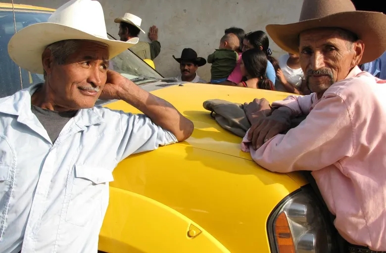 Two men wearing cowboy hats in Garifuna Village during a cultural journey