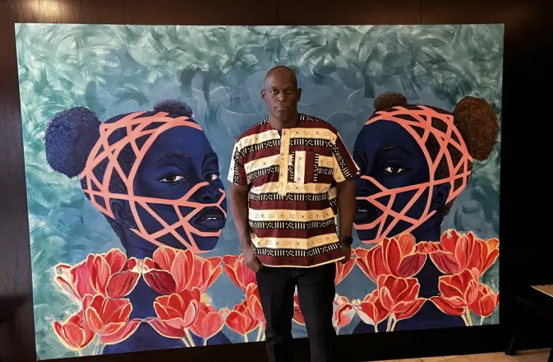 Martin stands before a large vibrant painting of two blue-toned figures with coral geometric patterns and red tulips.