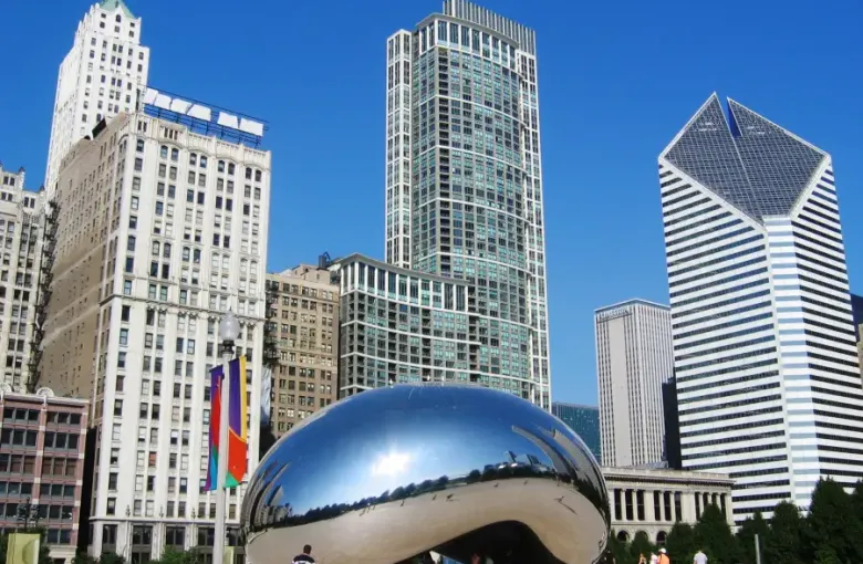 Cloud Gate sculpture reflecting Chicago Illinois skyline and skyscrapers in Millennium Park on a clear blue day