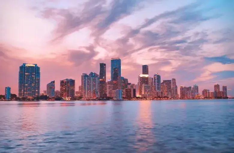 Miami Florida downtown skyline at sunset reflected over Biscayne Bay with dramatic pink and blue clouds