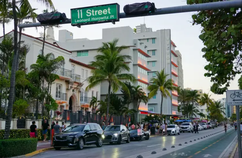 Ocean Drive at 11th Street in Miami; Florida; showing Art Deco hotels; palm trees; and evening traffic.