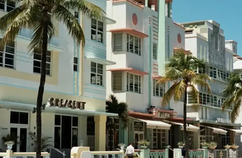 Art Deco hotels including the Crescent and Alpin line Ocean Drive in Miami Florida; flanked by palm trees under a clear bl