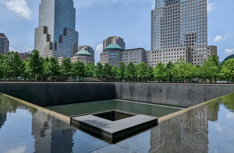 9/11 Memorial reflecting pool with cascading waterfall and Manhattan skyline in New York New York on a sunny day