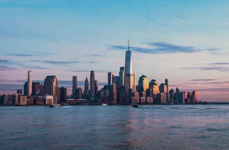 New York New York's Lower Manhattan skyline at sunset with One World Trade Center reflected in the Hudson River
