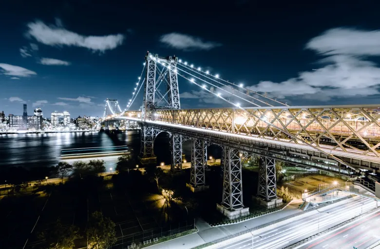 Queensboro Bridge spanning the East River in New York New York with city skyline and light trails from traffic below