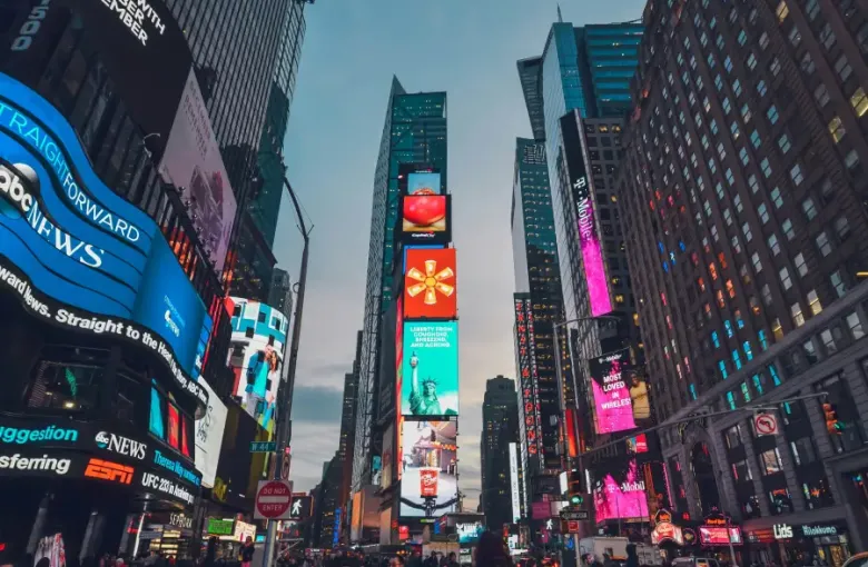 Glowing digital billboards and skyscrapers line Times Square in New York New York at dusk with crowds below