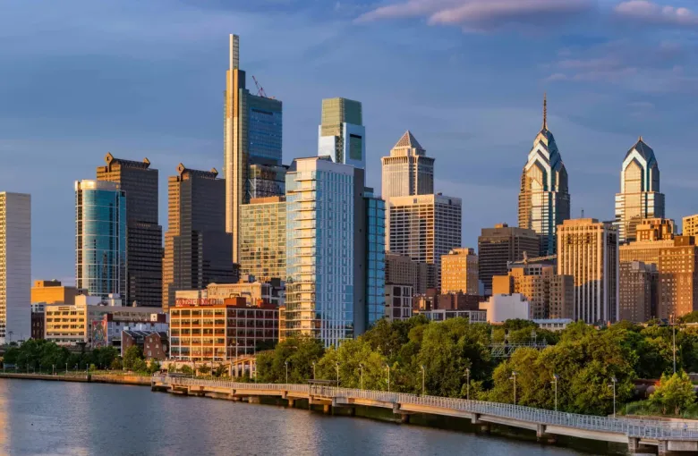 Philadelphia Pennsylvania downtown skyline at golden hour viewed across the Schuylkill River with highways and lush trees
