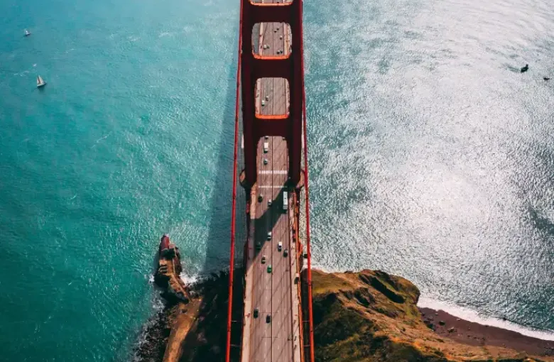 Aerial view looking down the Golden Gate Bridge in San Francisco; CA; with turquoise bay waters and light traffic below.