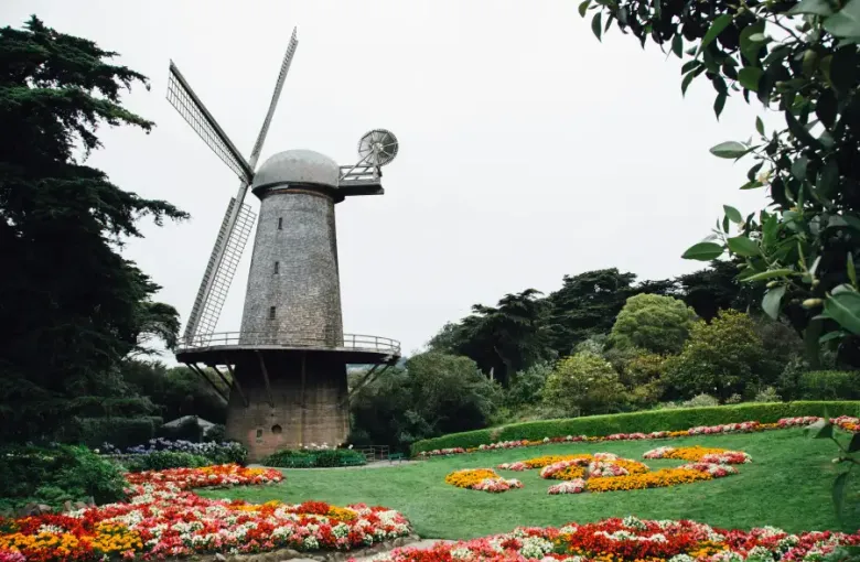 Dutch windmill surrounded by colorful flower gardens in Golden Gate Park; San Francisco; CA; under an overcast sky.