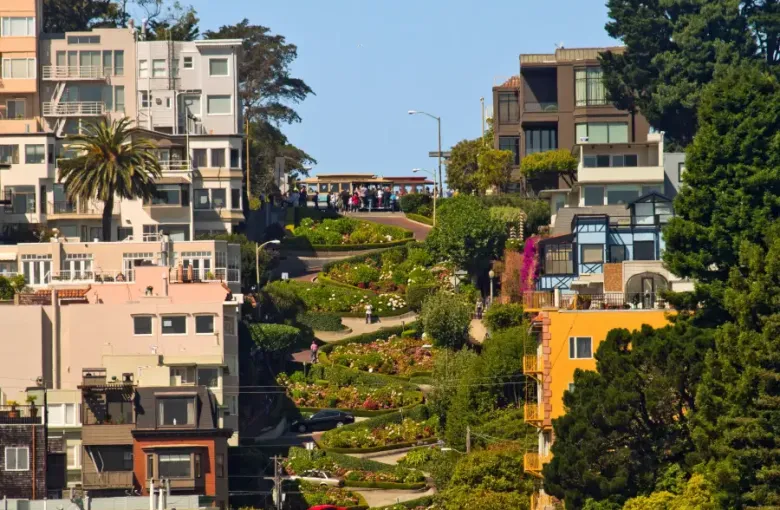Iconic winding Lombard Street in San Francisco; CA; lined with colorful flowers; historic buildings; and a cable car at th