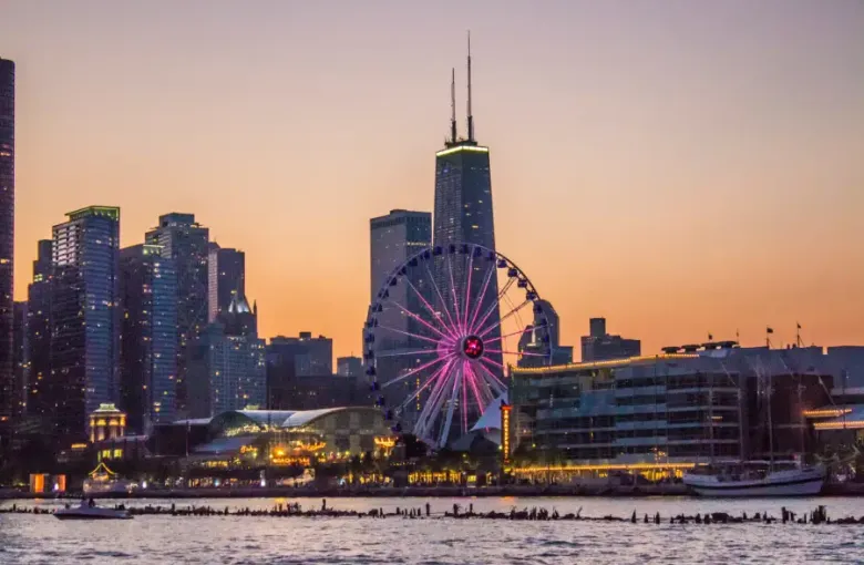 Chicago's Navy Pier Ferris wheel glowing pink at sunset with the John Hancock Center and city skyline behind; viewed from