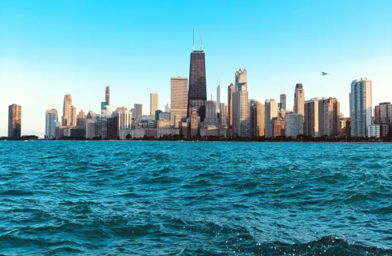Chicago skyline viewed from Lake Michigan; featuring the John Hancock Center rising above the city under a clear blue sky.