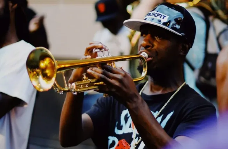 A New Orleans brass band trumpeter performing on the street with a sousaphone behind him