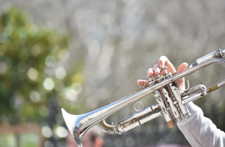A musician playing a silver trumpet outdoors in New Orleans, the birthplace of jazz