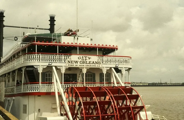A red paddlewheel steamboat docked on the Mississippi River in New Orleans